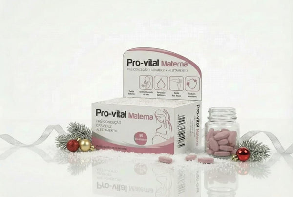 Embalagem de Pro-vital Materna com silhueta de grávida, exibida sobre neve artificial com um frasco de vidro cheio de comprimidos cor-de-rosa, decorada com fita prateada, ramos de pinheiro e bolas de Natal vermelhas e douradas.
